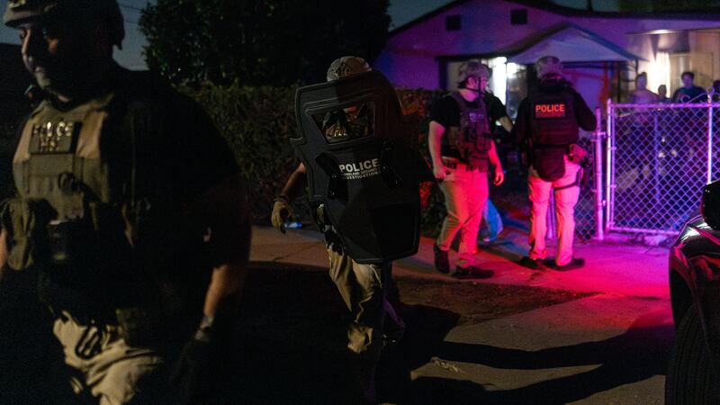 Agentes de Investigaciones de Seguridad Nacional salen de una residencia después de arrestar a...