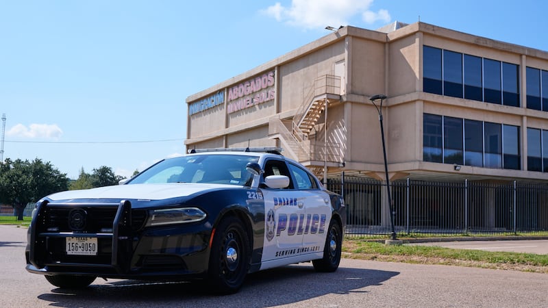 Un vehículo policial bloquea el paso cerca de una escena donde se cometió un delito junto a...