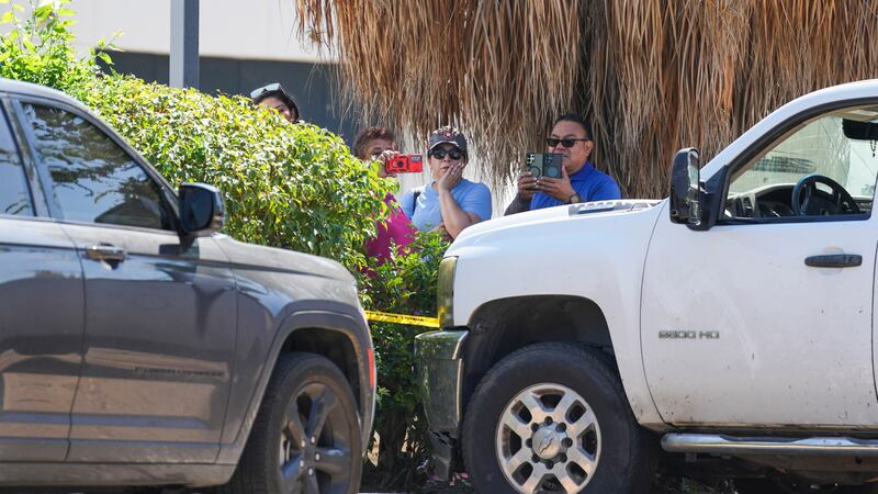 Varias personas observan mientras policías del condado Harris trabajan en el lugar cerca de...