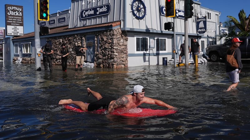 Un hombre surfea en una inundación, el miércoles 28 de octubre de 2026, en Huntington Beach,...
