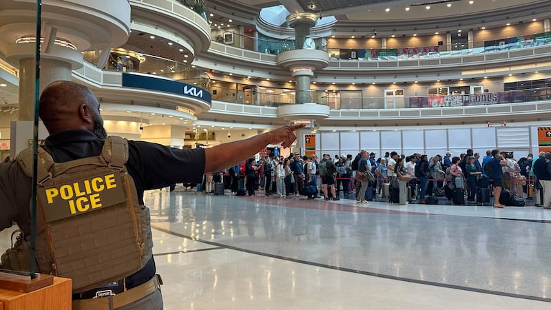 Un agente de inmigración se ve mientras gente espera en la línea del control de seguridad en...