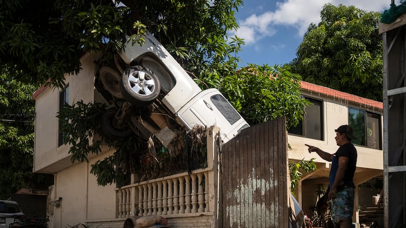 Una camioneta sobre la cerca de una residencia después de intensas lluvias e inundaciones, el...